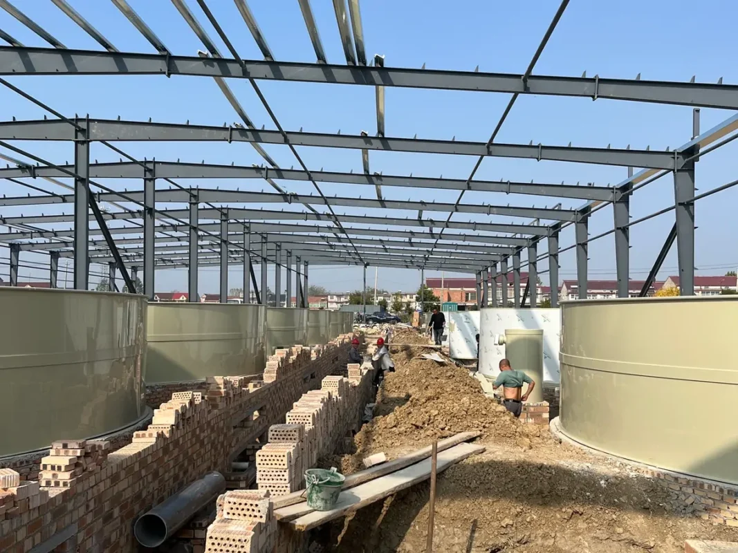 未完工中央沟槽旁成排的浅色池体及施工材料。