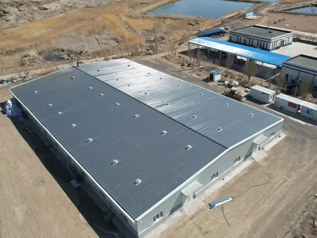 室外水体旁大型灰色屋顶建筑的斜向航拍图。