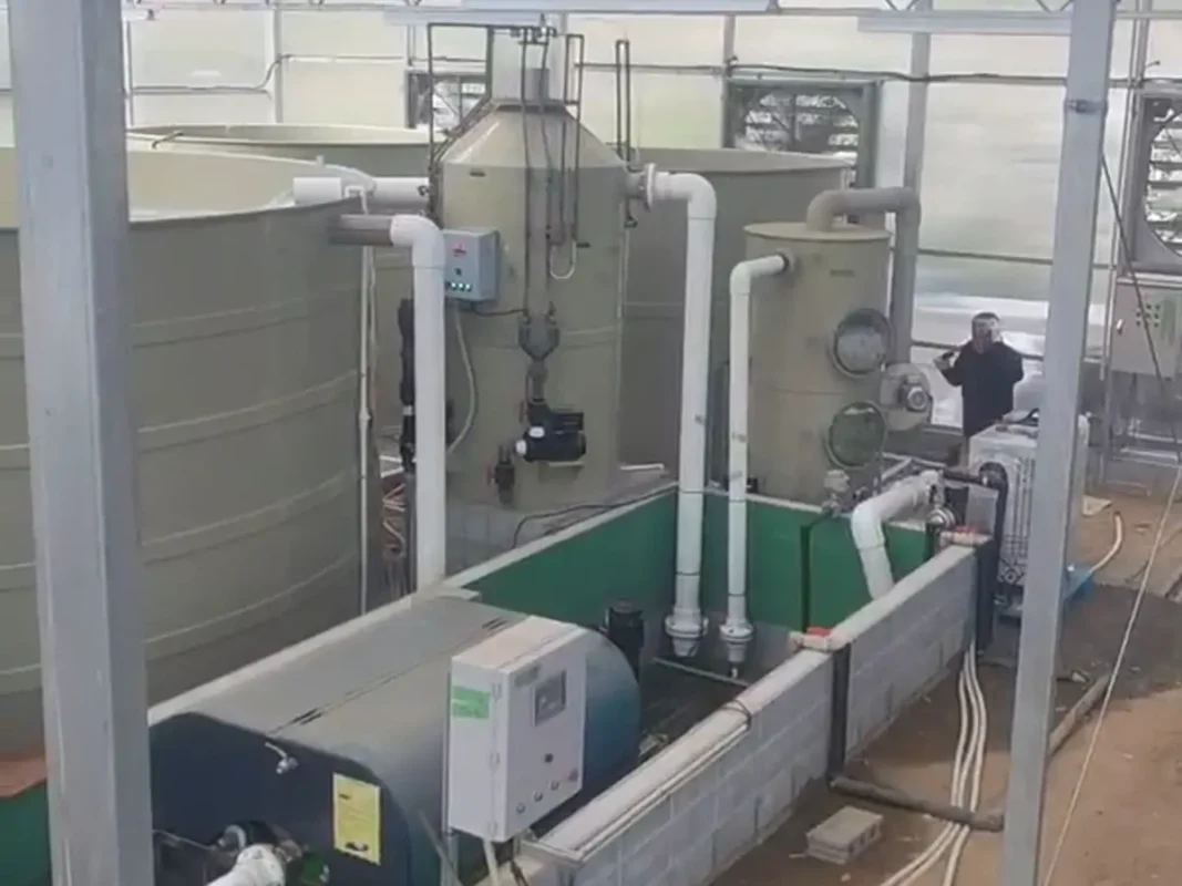 养殖池旁的立式圆柱形容器、阀门和白色管道。