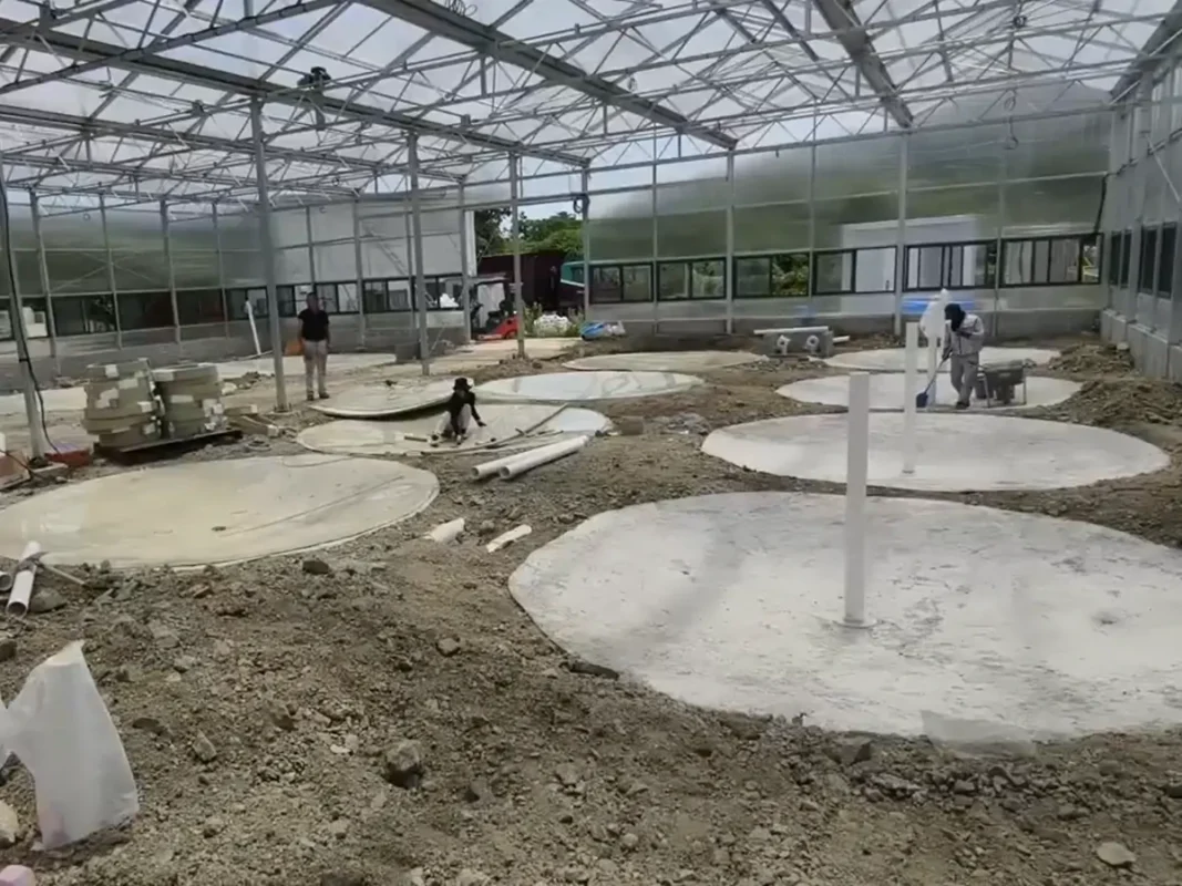 工作人员在温室式建筑内部准备圆形混凝土池基。