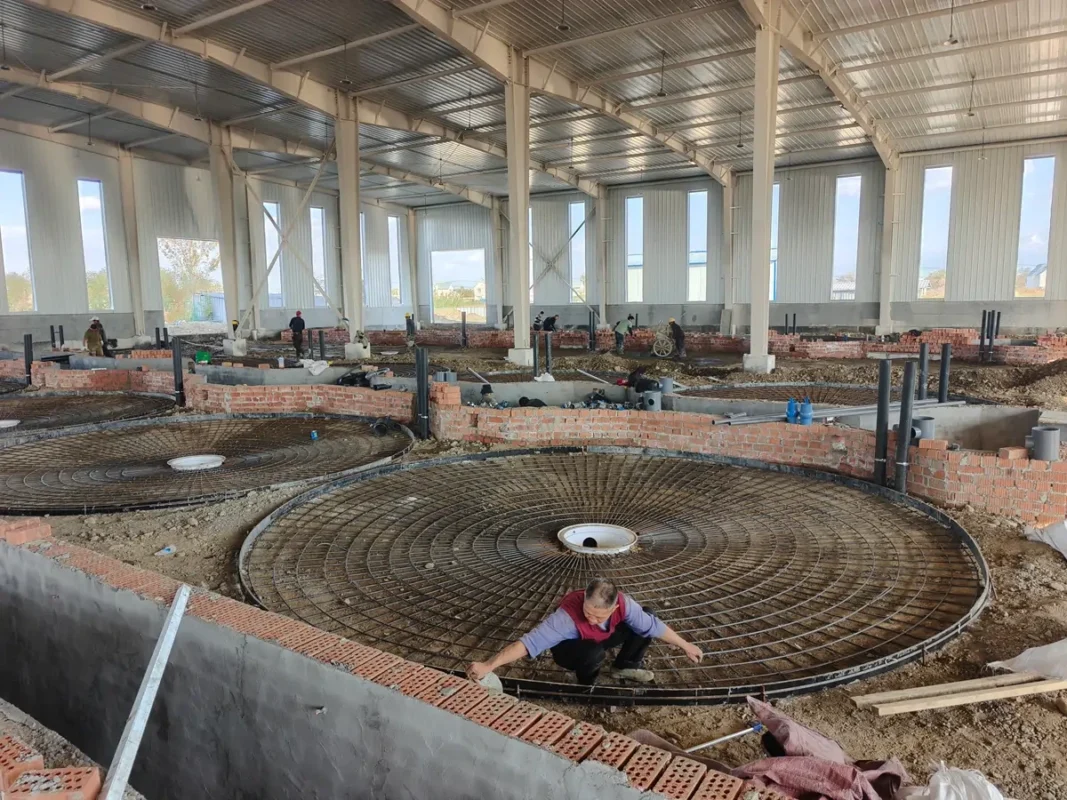 建筑内部的圆形钢筋笼及准备池基的工作人员。