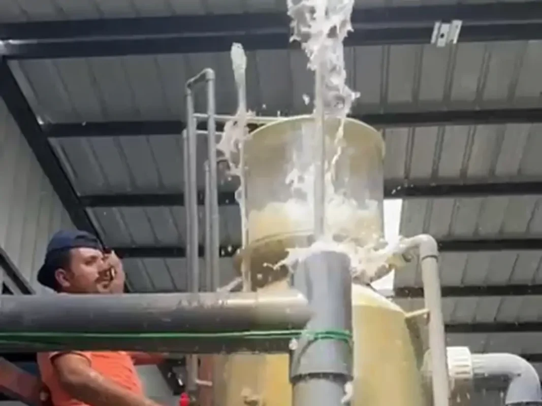立式容器旁的人员，以及可见水流和连接管道。